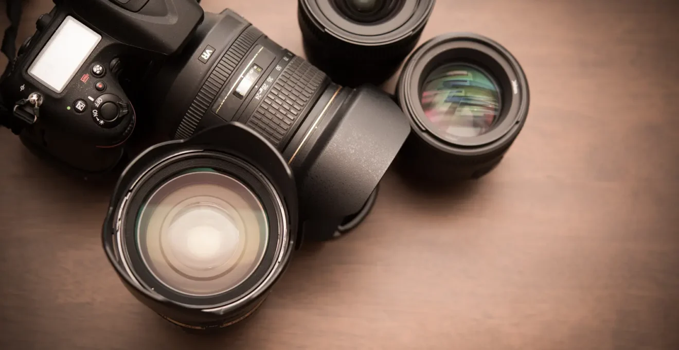 Gros plan sur les mains d'un photographe réglant la bague d'ouverture d'un objectif avec les valeurs f visibles.
